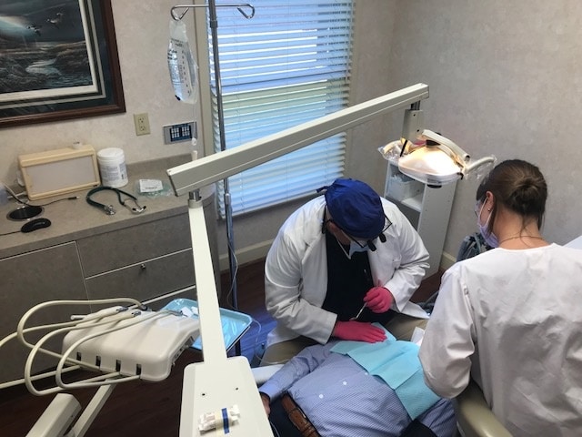Dentist and his assistant actively working on a relaxed patient